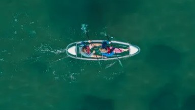 Aerial view of a person kayaking on clear green water.